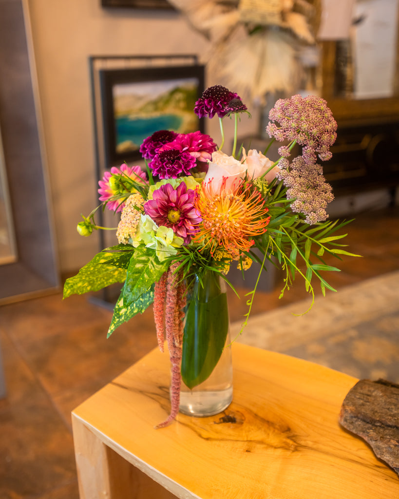 A compact yet brimful floral mix, slender glass vase
