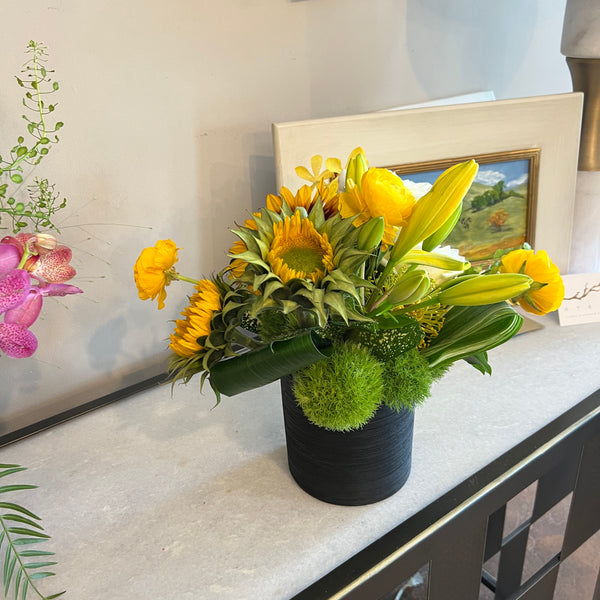 Sunflower dominant, clustered foliage, black ceramic container