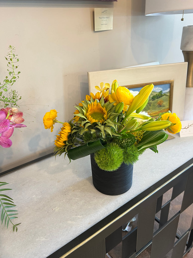 Sunflower dominant, clustered foliage, black ceramic container