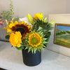 Sunflower dominant, clustered foliage, black ceramic container