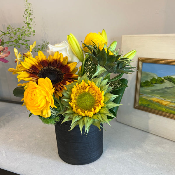 Sunflower dominant, clustered foliage, black ceramic container